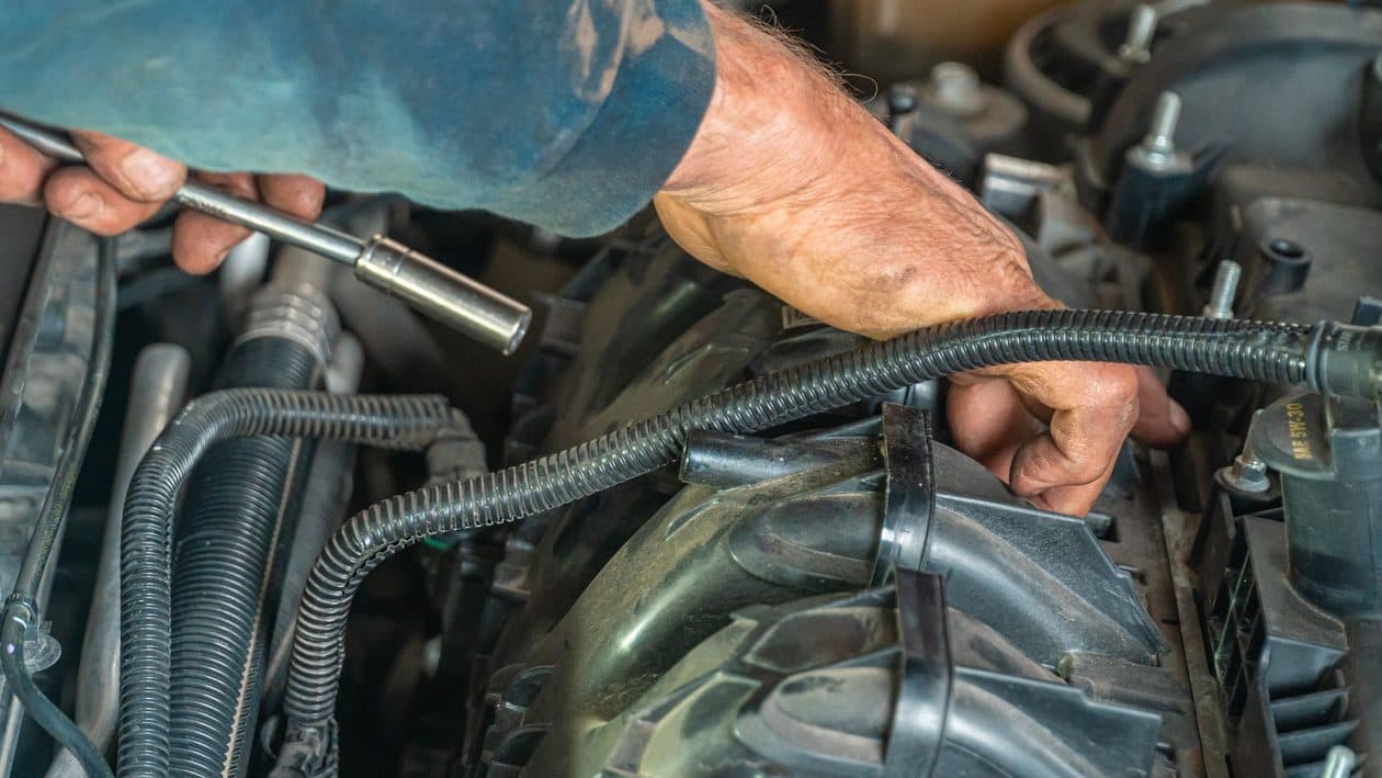 Manos de mecánico trabajando en el motor de un auto